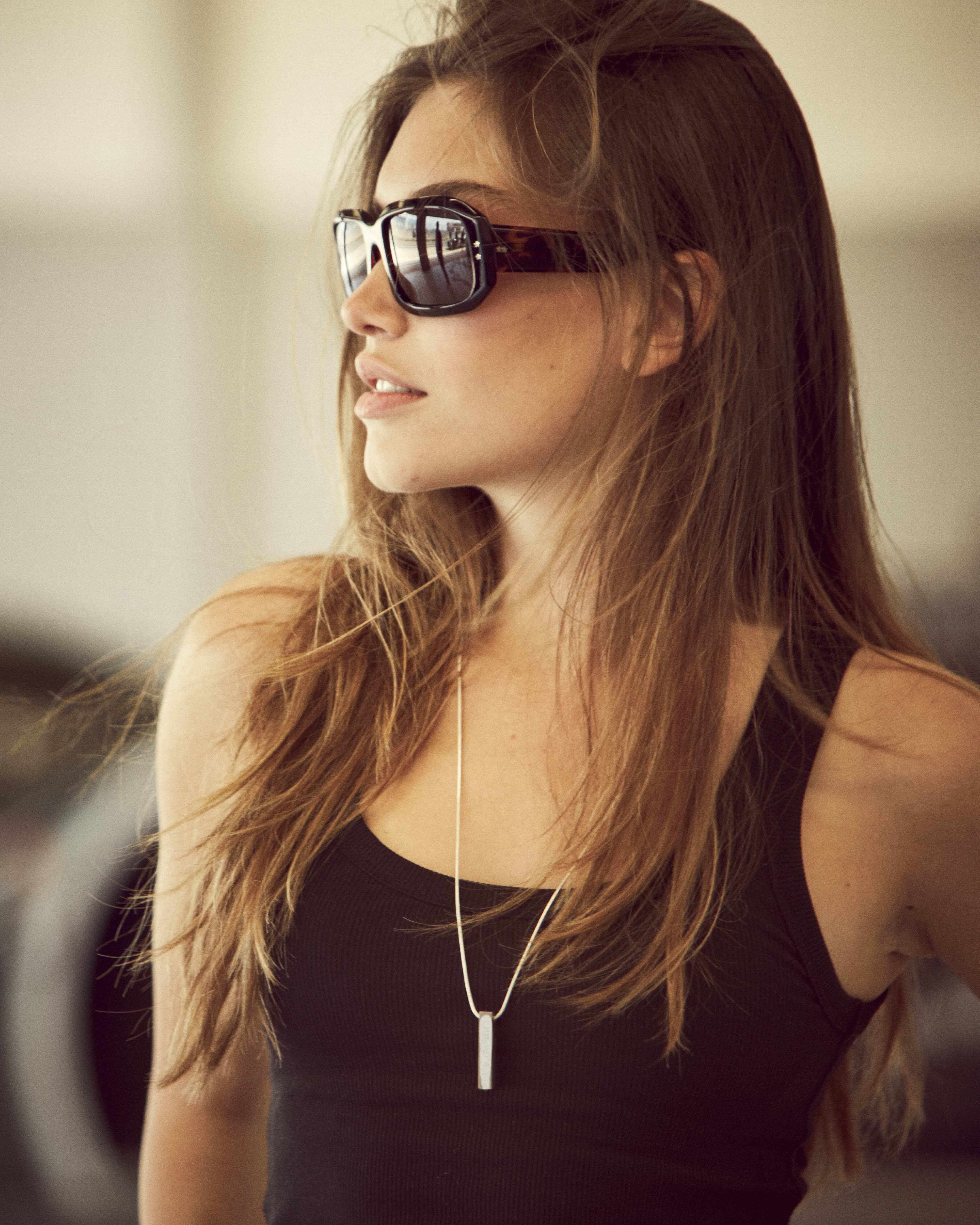 Female model wearing a RESS necklace made from an F1 car stood in the pit lane at Silverstone circuit in the UK. 